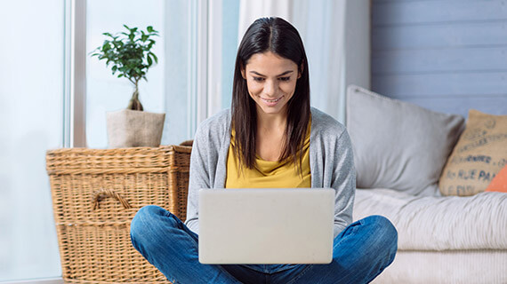 Young woman sitting down with laptop on her lap