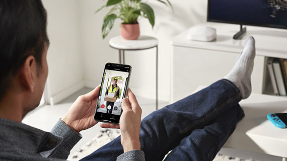 Man sitting on couch looking at doorbell video feed on his phone