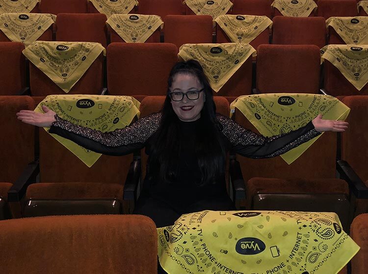 Vyve employee poses with Vyve branded bandanas in a theatre