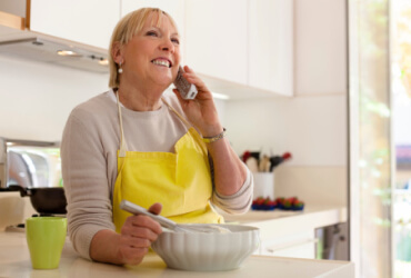 Woman in the kitchen on a cordless phone while baking
