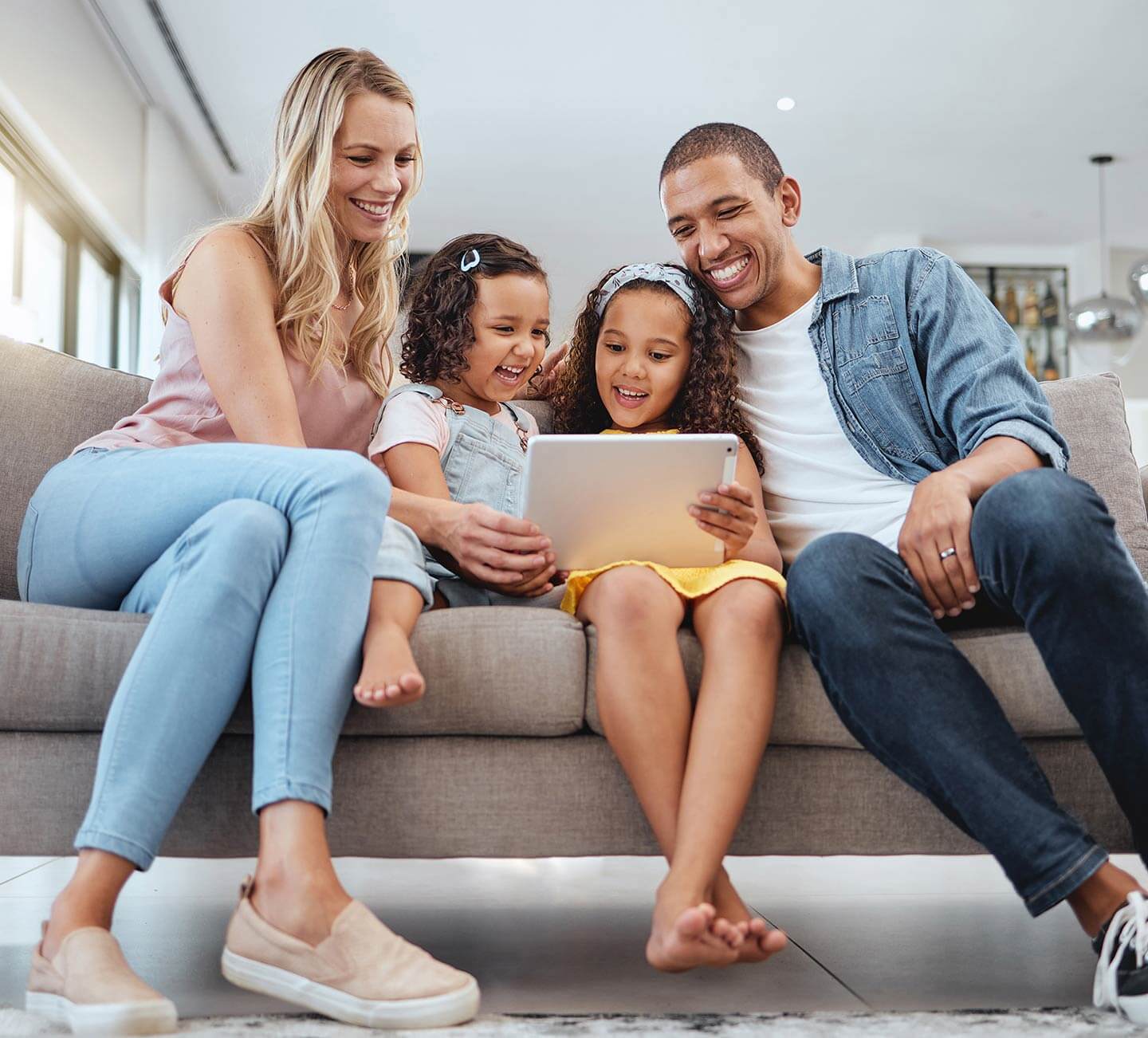 Smiling family sitting on a couch viewing a tablet together