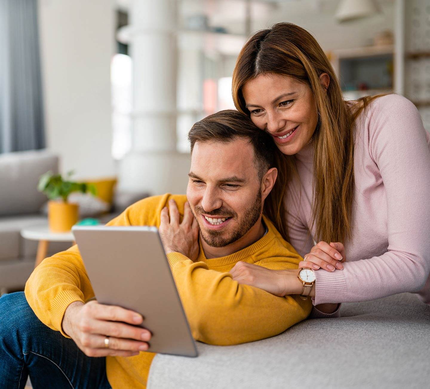 Husband and wife smiling as they view a tablet together