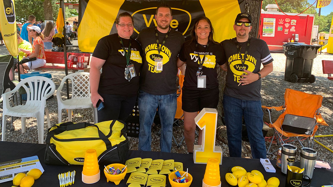 Vyve Sales team members pose behind a table of Vyve swag